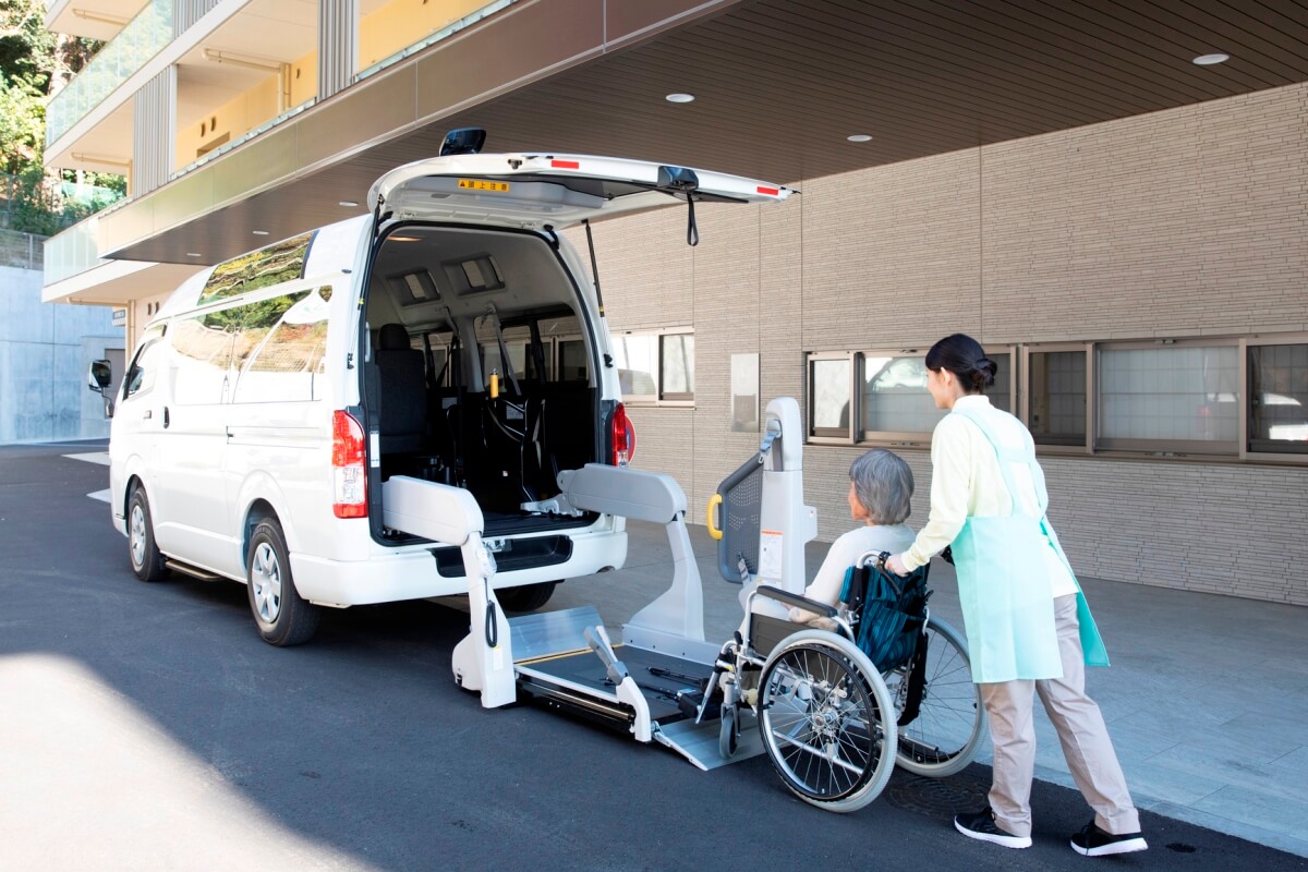 リフトに車いす利用者を乗せるヘルパー