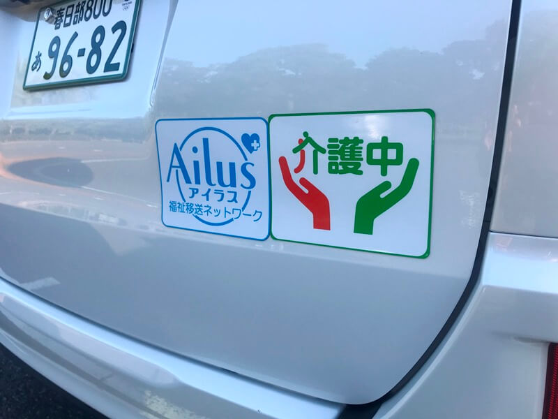 車両のリアに貼った福祉移送ネットワークアイラスのステッカーと介護中ステッカー