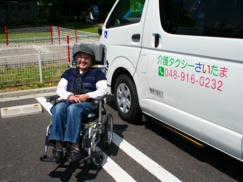 車両の前で車いすに乗った笑顔のお客様